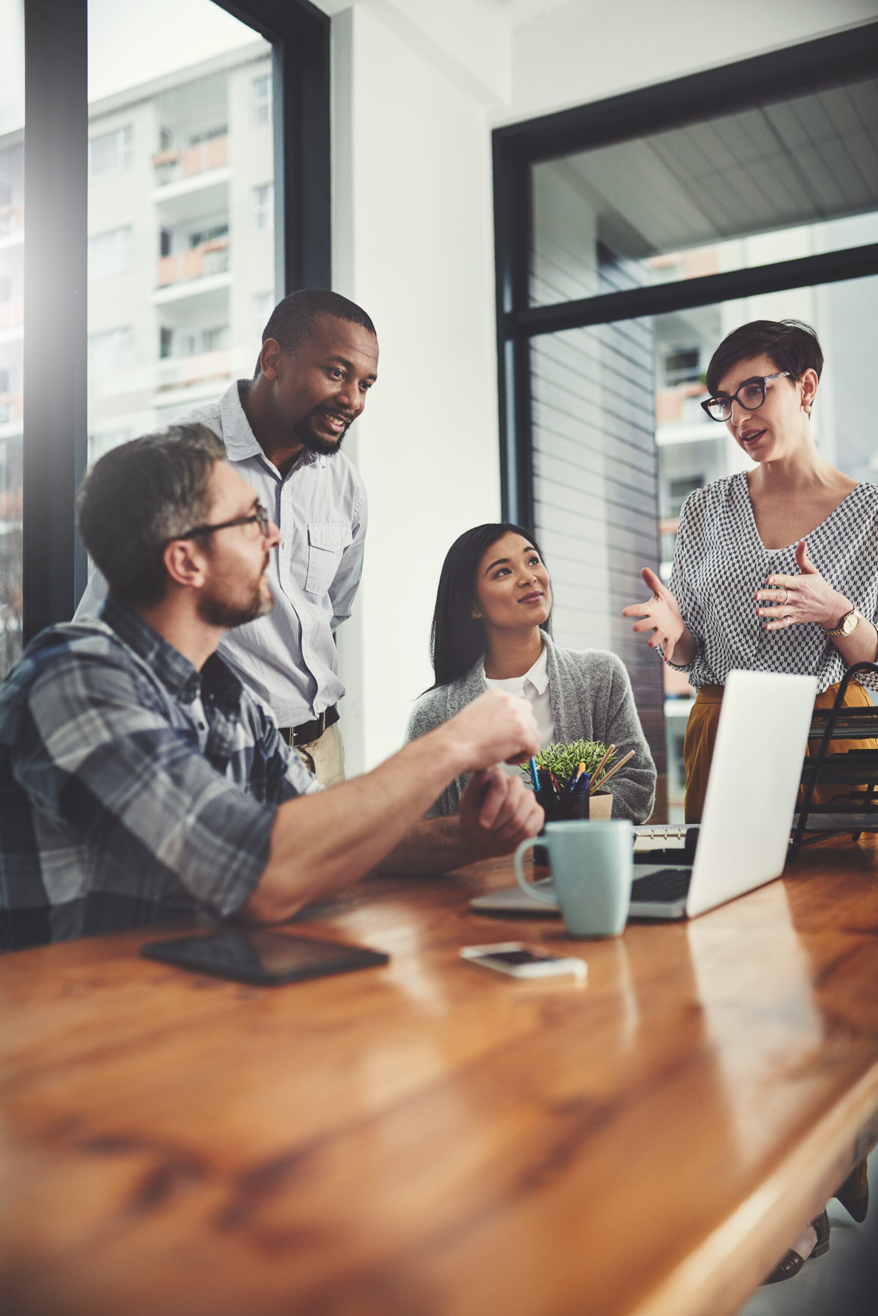 Teamwork, laptop and coaching with business people in meeting for project management, review or planning. Technology, website and training with group of employees in office for collaboration and idea.